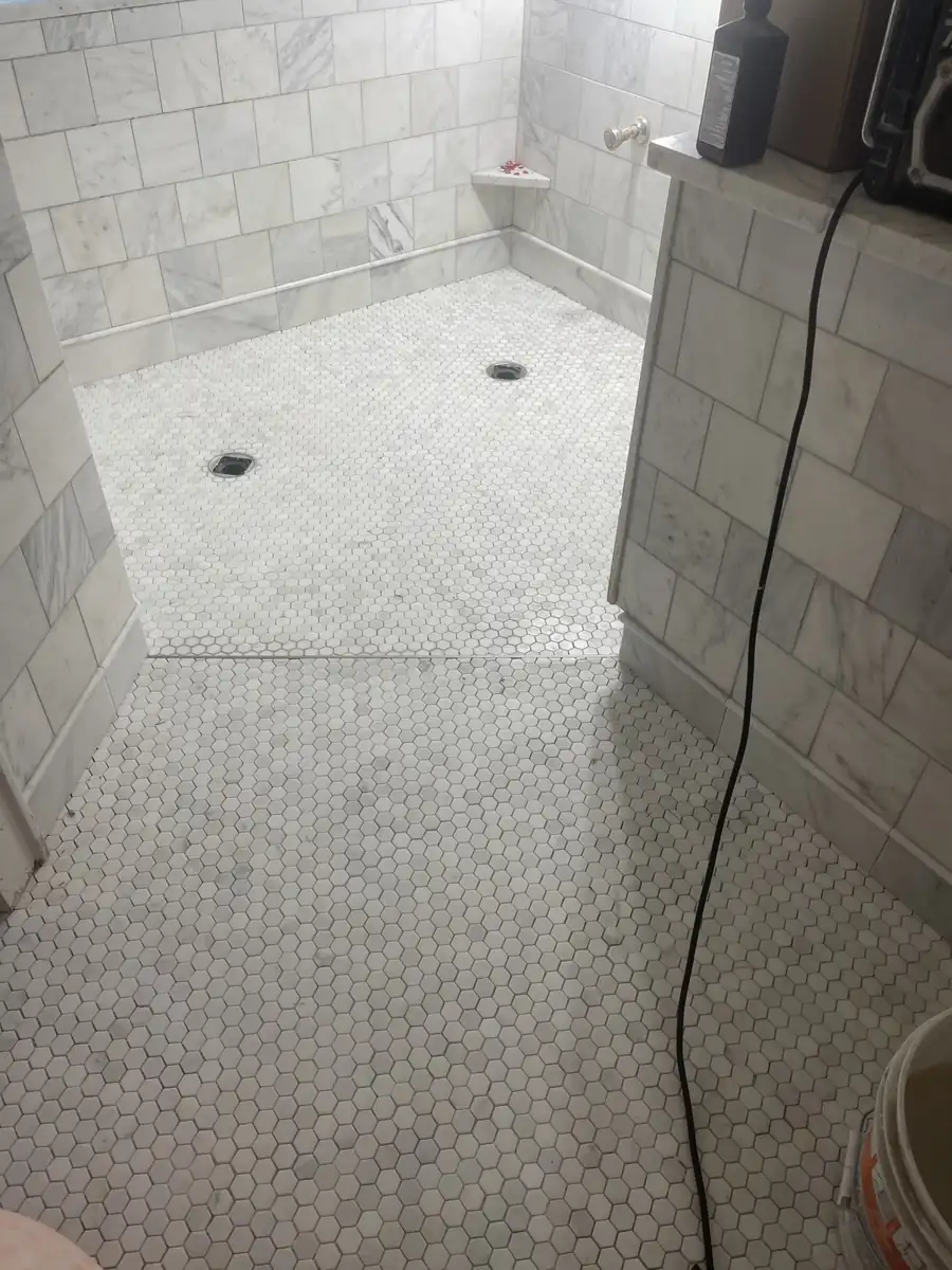 Finished marble shower with a hexagon mosaic floor