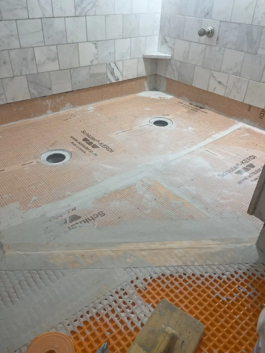 Schluter KERDI shower pan and mud curb below marble walls