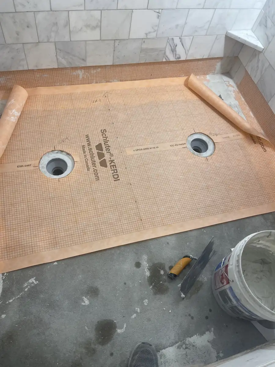 Schluter KERDI membrane bonded over the mortar bed around two drains
