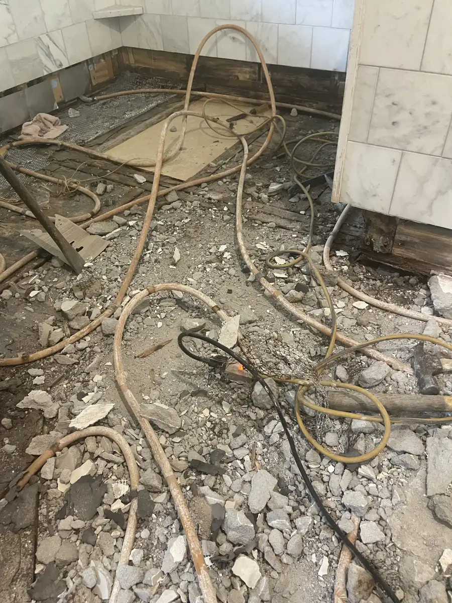 Shower floor demolished to the joists with radiant tubing exposed