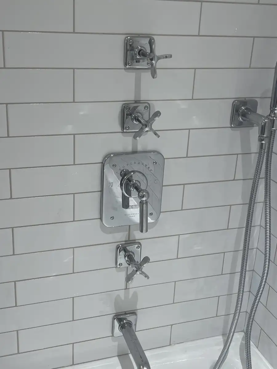 Subway tile shower wall with fixture escutcheons cut in cleanly