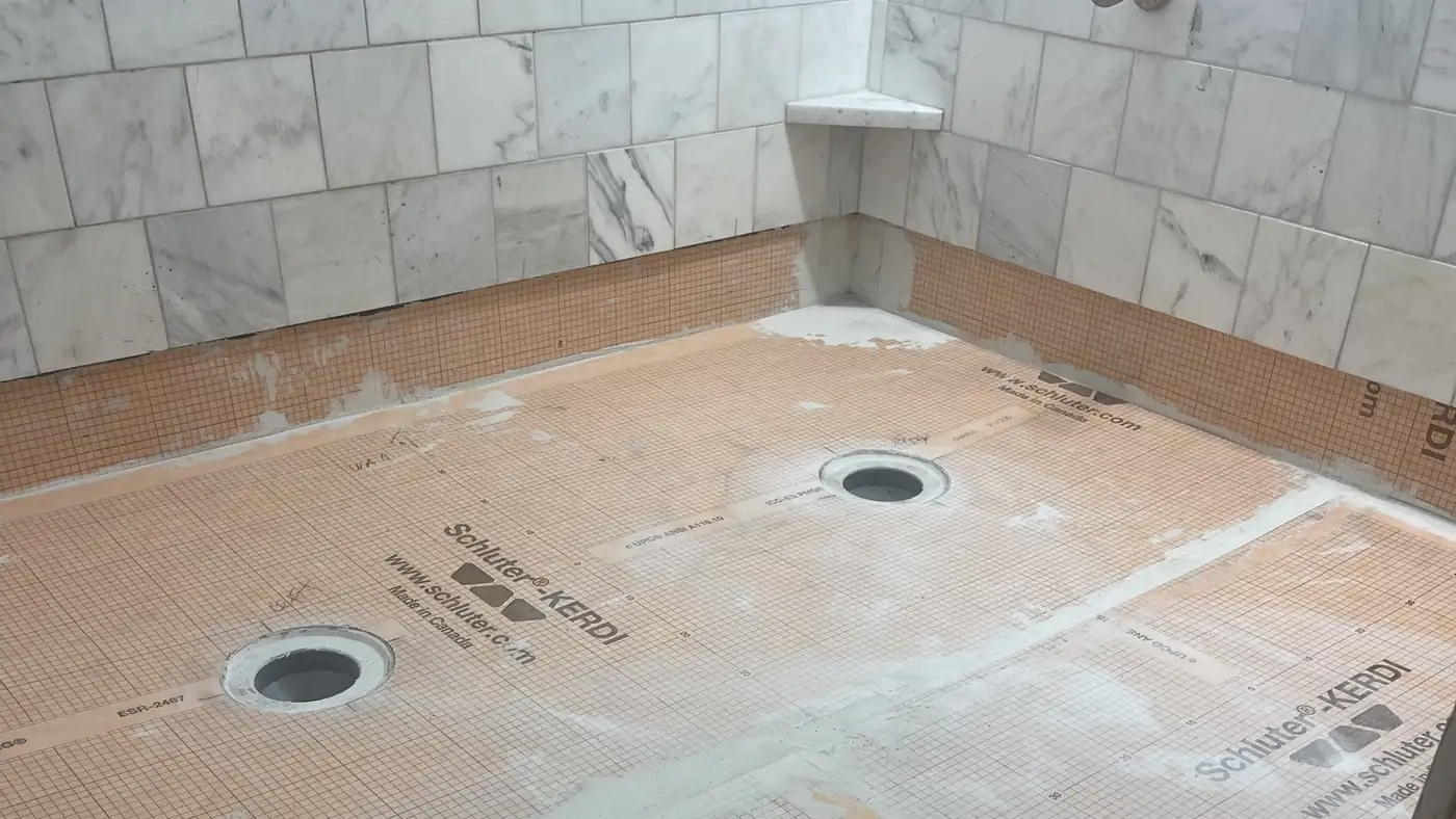 Schluter KERDI shower pan and mud curb below marble walls